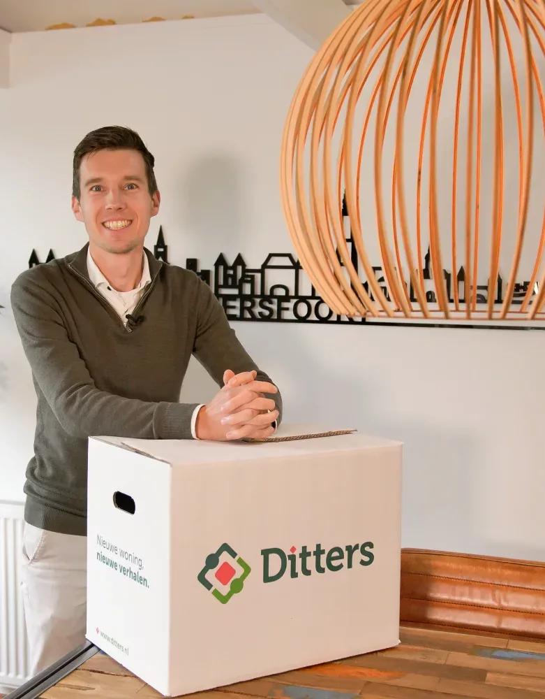 Een medewerker van Ditters Makelaars Amersfoort ondersteunt klanten bij de verkoop van hun woning en de voorbereidingen op hun volgende woonsituatie, weergegeven met een Ditters-verhuisdoos.