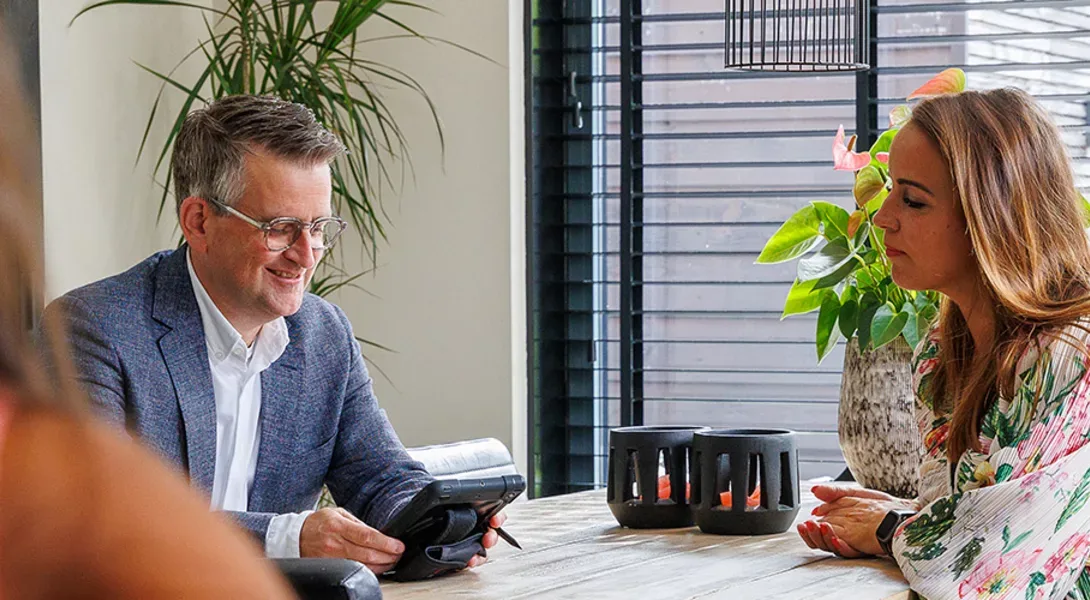 Makelaar van Ditters voert een taxatiegesprek met klant aan tafel, deskundig advies over woningwaarde.