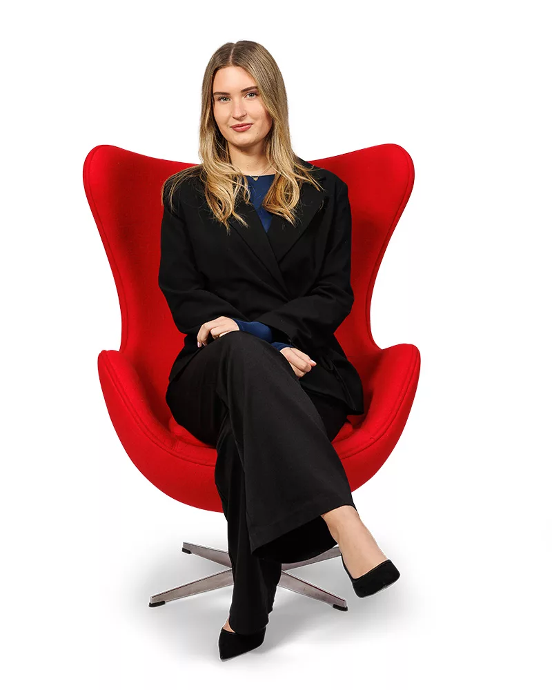 Isa van Ditters, front office, portret in rode stoel met witte achtergrond.