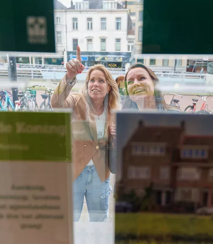 Etalage Ditters Makelaars Arnhem – woningaanbod bekijken in het centrum Twee geïnteresseerden bekijken het woningaanbod in de etalage van Ditters Makelaars in het centrum van Arnhem.
